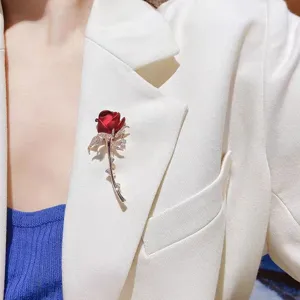 Detailed view of an elegant red rose brooch with crystals pinned to a white suit lapel