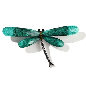 Detailed macro shot of a green resin dragonfly brooch with brushed texture details