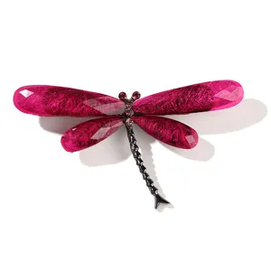 Close-up of magenta resin dragonfly brooch with textured wings and rhinestones