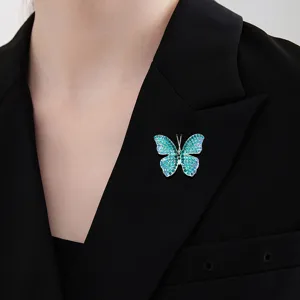 Elegante spilla a farfalla con strass blu su un risvolto di una giacca nera formale.
