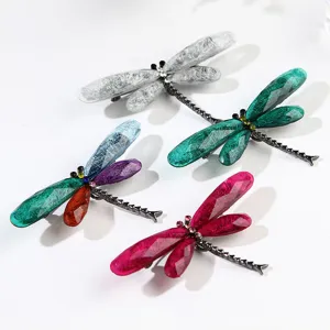 Detailed view of colorful dragonfly brooches with textured resin wings and rhinestones