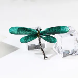 Exquisite close-up of green dragonfly brooch with brushed resin wings and crystal accents.