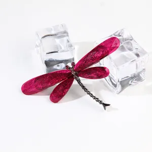 Detailed close-up of a pink resin dragonfly brooch featuring unique brushed texture wings