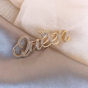 Detail van gouden Queen-woordbroche met kroon en pavé strassteentjes