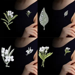 Elegantes broches botánicos verdes con perlas para refinados accesorios de moda femenina.