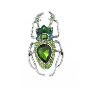 Macro detail of a vintage beetle brooch featuring vibrant green crystals and silver metal