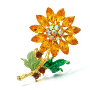 Detailopname van een zonnebloem broche met barnsteen strassteentjes en groene emaille