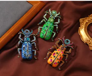 Nahaufnahme von drei bunten Vintage-Emaille-Skarabäus-Broschen mit glänzenden Kristallen