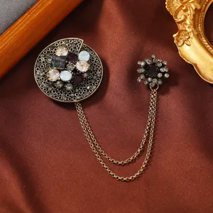 Vintage style antique gold brooch featuring rhinestone details and a double tassel chain