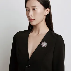 Broche baroque ajourée avec pierres rouges et vertes sur un blazer noir