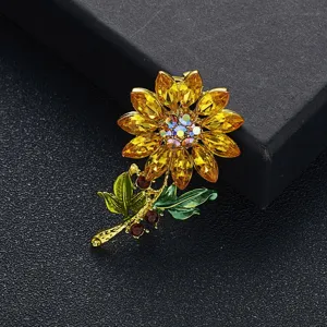 Gedetailleerd macrozicht van een zonnebloem broche met gele kristallen en groene bladeren