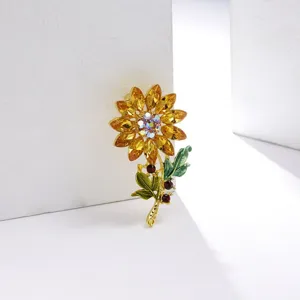 Elegante zonnebloem broche met gele strassteentjes en groene emaille blaadjes voor kleding.