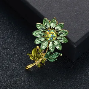 Detailopname van prachtige zonnebloem broche met groene strass en een gouden basis