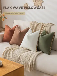 Detailansicht von farbigen Leinenkissenbezügen mit gewellten Stickkanten auf Sofa.