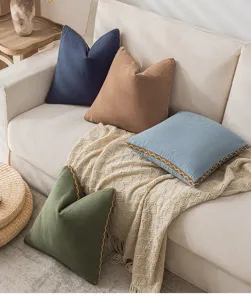 Detailaufnahme von Kissenbezügen aus Baumwollleinen mit Wellenrand auf einem cremefarbenen Sofa