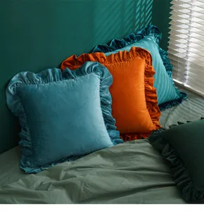 Nahaufnahme von eleganten Samtkissenbezügen mit Rüschen in Blau und Orange für Sofas