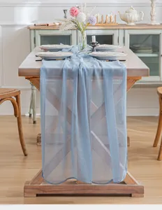 Elegante camino de mesa de gasa azul claro sobre una mesa de comedor de madera