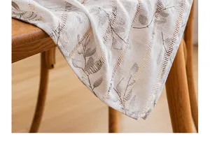 Close-up of white hollow-stripe tablecloth with artistic leaf prints and soft texture