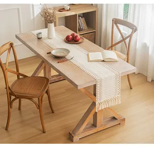 Bohemian woven cotton linen table runner with tassels on a wooden dining table.