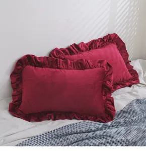 Detailansicht von weinroten Samtkissenbezügen mit eleganten Rüschenrändern und Falten.