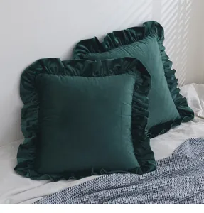 Dunkelgrüne Samtkissenbezüge mit eleganten Rüschenrändern auf einem weißen Bett