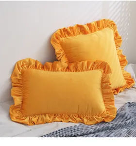 Nahaufnahme des goldgelben Samtkissenbezugs mit Rüschen zeigt weiche Stofftextur und Details.