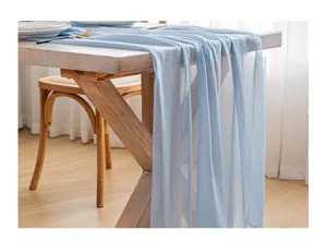 Detalle de camino de mesa de gasa azul claro con textura transparente y caída suave