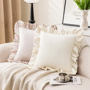 Cream and pink velvet ruffled pillowcases on a cozy sofa with knitted throw blanket.
