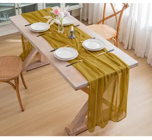 Camino de mesa de gasa amarillo mostaza drapeado sobre una mesa de madera rústica