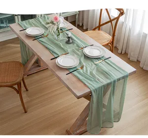 Camino de mesa de gasa verde salvia sobre mesa de madera para decoración de bodas
