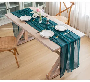 Elegante camino de mesa de gasa verde esmeralda sobre una mesa de comedor de madera