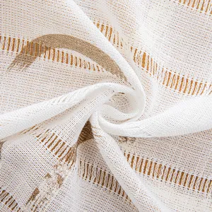 Detail of white hollow stripe tablecloth with gold floral print and linen texture