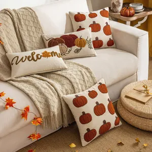 Gemütliche herbstliche Kissenbezüge mit Kürbis-Stickerei auf einem Sofa mit Herbstdeko