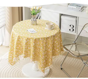 Yellow floral tablecloth with cream tassels displayed on a round table in a bright room