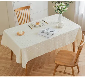 Detail of a cream tufted rectangular tablecloth showing texture on a wooden dining table