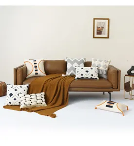 Set getufte boho kussenslopen met geometrische patronen op een bruine leren bank