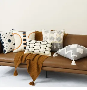 Boho geometrische getufte sierkussens met kwastjes op bruine leren bank