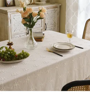 Detailed view of white lace tablecloth with 3D floral embroidery on a dining table