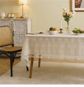 Detailed view of white floral embroidered lace tablecloth on a wooden dining table