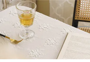 Detail of white lace tablecloth with exquisite 3D floral embroidery in French style.