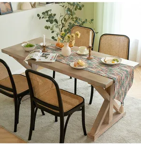 Runner da tavola boho colorato con motivi a zigzag e nappe su un tavolo da pranzo in legno