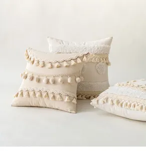 Close-up detail of bohemian style cushion covers featuring tassels and pompom fringes.