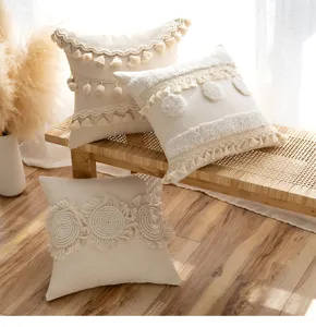 Detailed shot of cream bohemian pillow covers with tassels and poms on a wooden bench