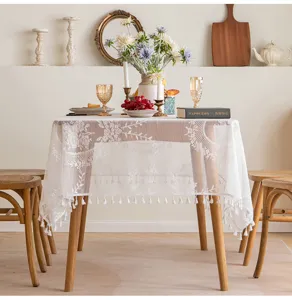 Detailed view of white French lace tablecloth featuring elegant floral embroidery and tassels