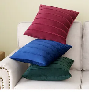 A stack of burgundy blue and green velvet cushion covers featuring elegant horizontal pleats
