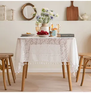 French lace rectangular tablecloth with floral embroidery and tassel fringe on a dining table.