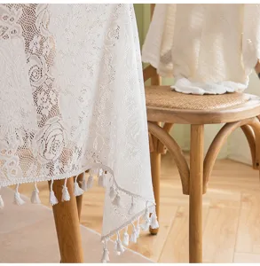 Detailed macro view of elegant white French lace tablecloth with floral patterns and tassels