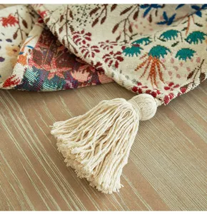 Dettaglio runner da tavola jacquard bohémien con nappa in cotone crema su legno