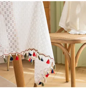 Close-up of white French lace tablecloth with vibrant colorful tassels and mesh texture