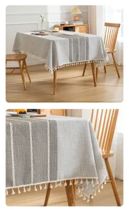 Vista detallada del mantel de lino gris con patrón de rayas y borlas de color crema